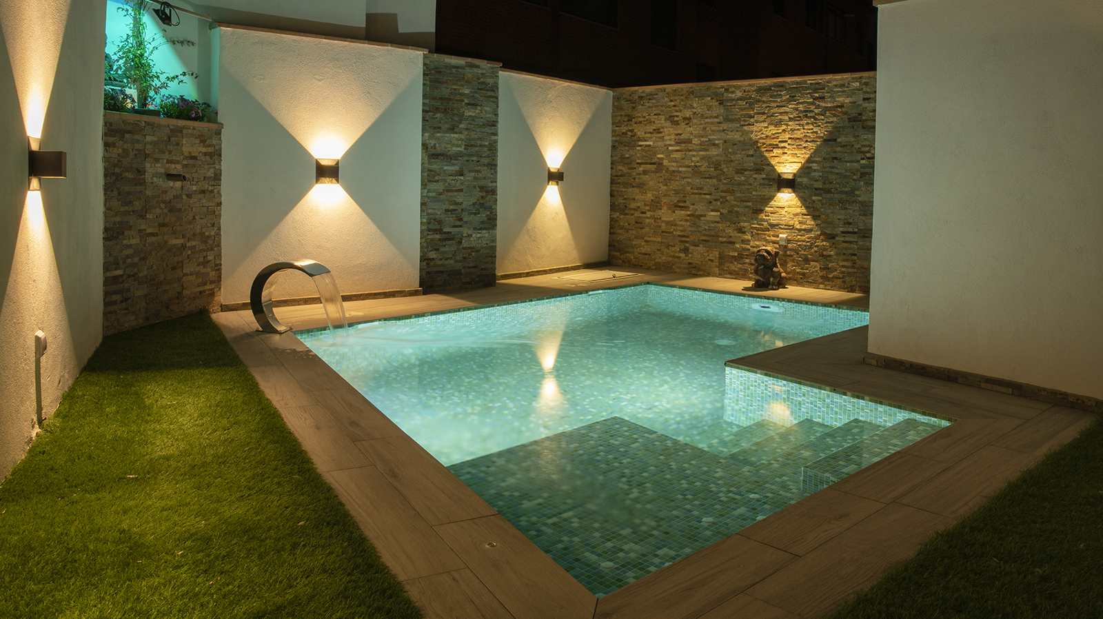 Sencilla y coqueta piscina en patio interior de vivienda en vista nocturna