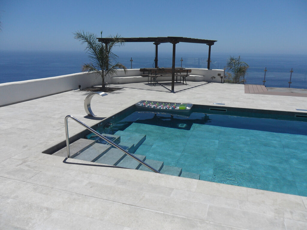 Detalle de escalera en piscina construída en interior y exterior con piedra porcelánica antideslizante