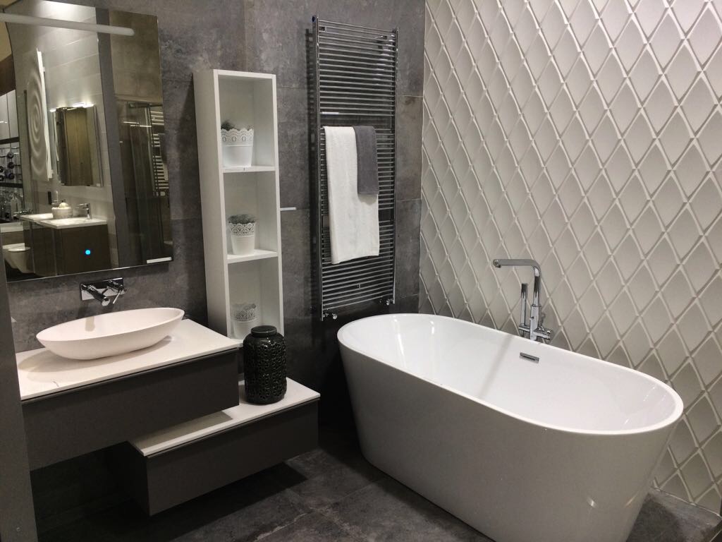 Ambiente de elegante baño con paredes combinadas de piezas cerámicas efecto industrial y romboidales en color blanco y acabado mate con relieve