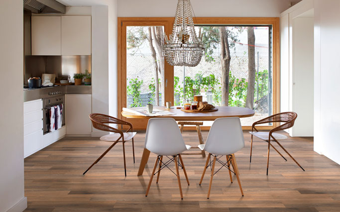 Salón comedor que continua con el porche pavimentado en madera cerámica