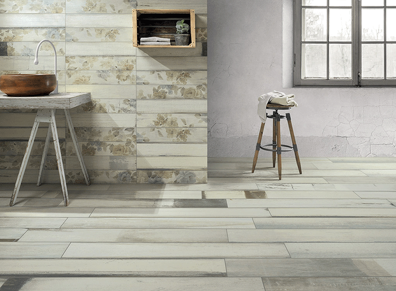 Sala de baño con suelo de madera porcelánica en color claro y pared revestida con piezas cerámicas de efecto papel pintado con motivos florales